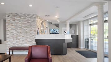 A reception area with a stone wall, a reception desk, a leather chair, and a large window.