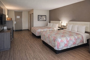 A hotel room with two beds, a desk, a TV, and a door. - Motel 6 – Lake City, Fl – Medical Center (Lake City)