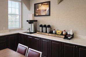 A kitchen with a coffee station, including a coffee maker, cups, and condiments. - Motel 6 – Lake City, Fl – Medical Center (Lake City)