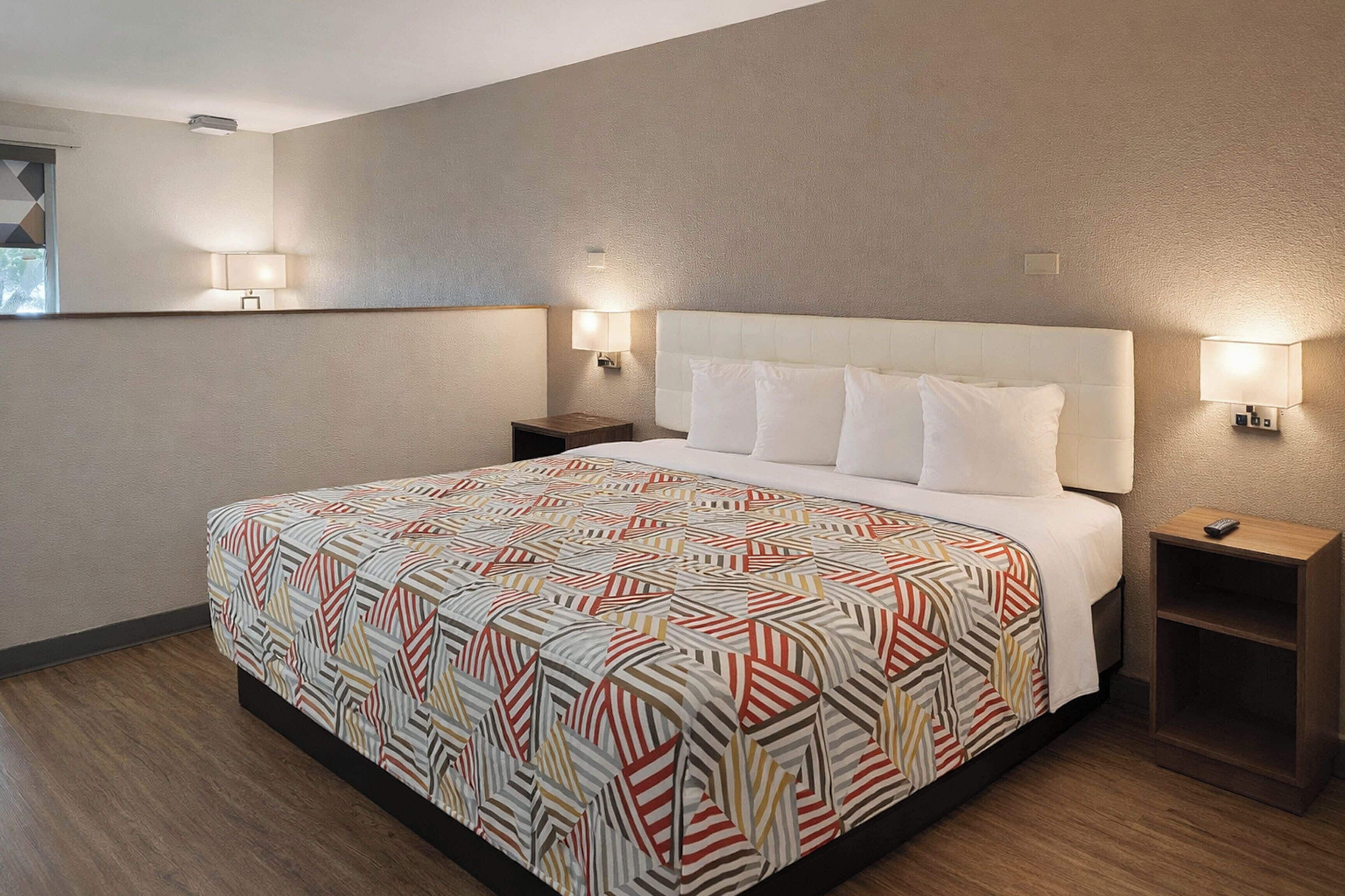 A hotel room with a large bed, two bedside tables, and wall-mounted lamps.