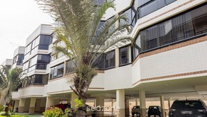 A modern multi-story residential building with balconies, a covered parking area, and a palm tree. - Beautiful Apartment in Asa Norte Brasilia Hin0117 (Brasília)