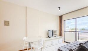 A modern living room with a sofa, a TV on a white console, and a dining area with a table and chairs. - Beautiful Apartment in Asa Norte Brasilia Hin0117 (Brasília)