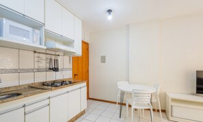 A modern kitchen with white cabinets, a granite countertop, and a gas stove. There is a dining area with a white table and chairs. - Beautiful Apartment in Asa Norte Brasilia Hin0117 (Brasília)