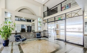 A spacious lobby with a high ceiling, a staircase, and a glass door leading outside. - Beautiful Apartment in Asa Norte Brasilia Hin0117 (Brasília)