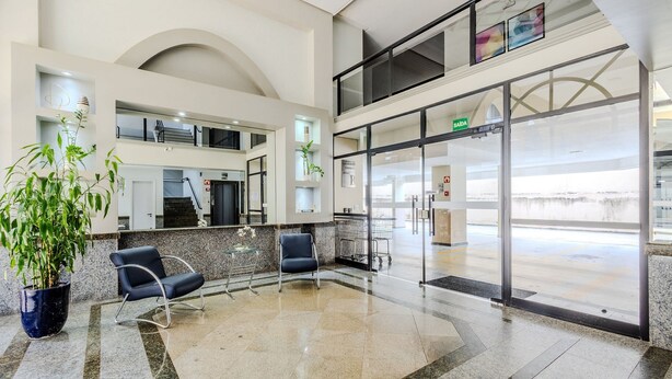 A spacious lobby with a high ceiling, a staircase, and a glass door leading outside. - Beautiful Apartment in Asa Norte Brasilia Hin0117 (Brasília)