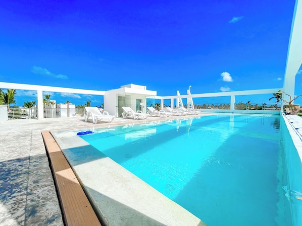 Una piscina al aire libre, sombrillas, tumbonas