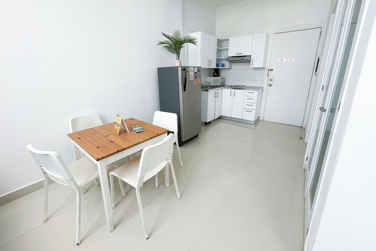 Uma cozinha compacta com armários brancos, uma geladeira e um micro-ondas.