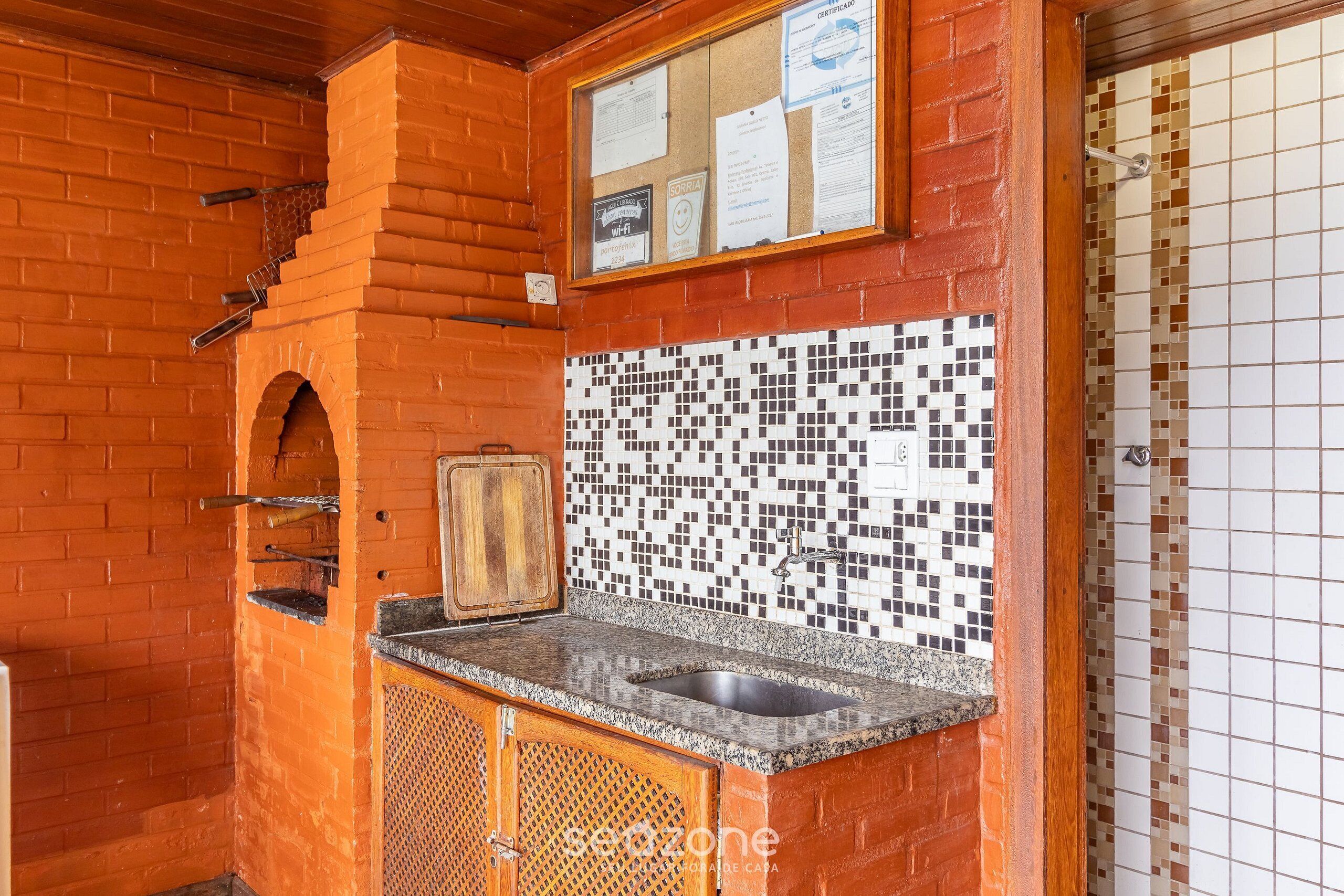 A kitchen with a tiled backsplash, a brick wall, and a wooden cabinet.