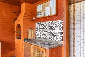 A kitchen with a tiled backsplash, a brick wall, and a wooden cabinet. - Duplex Overlooking Channel Cabo Frio-rj Fnx0101 (Cabo Frio)