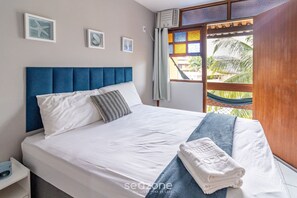 A neatly made bed with white and blue bedding, a blue headboard, and a hammock visible through a window. - Duplex Overlooking Channel Cabo Frio-rj Fnx0101 (Cabo Frio)