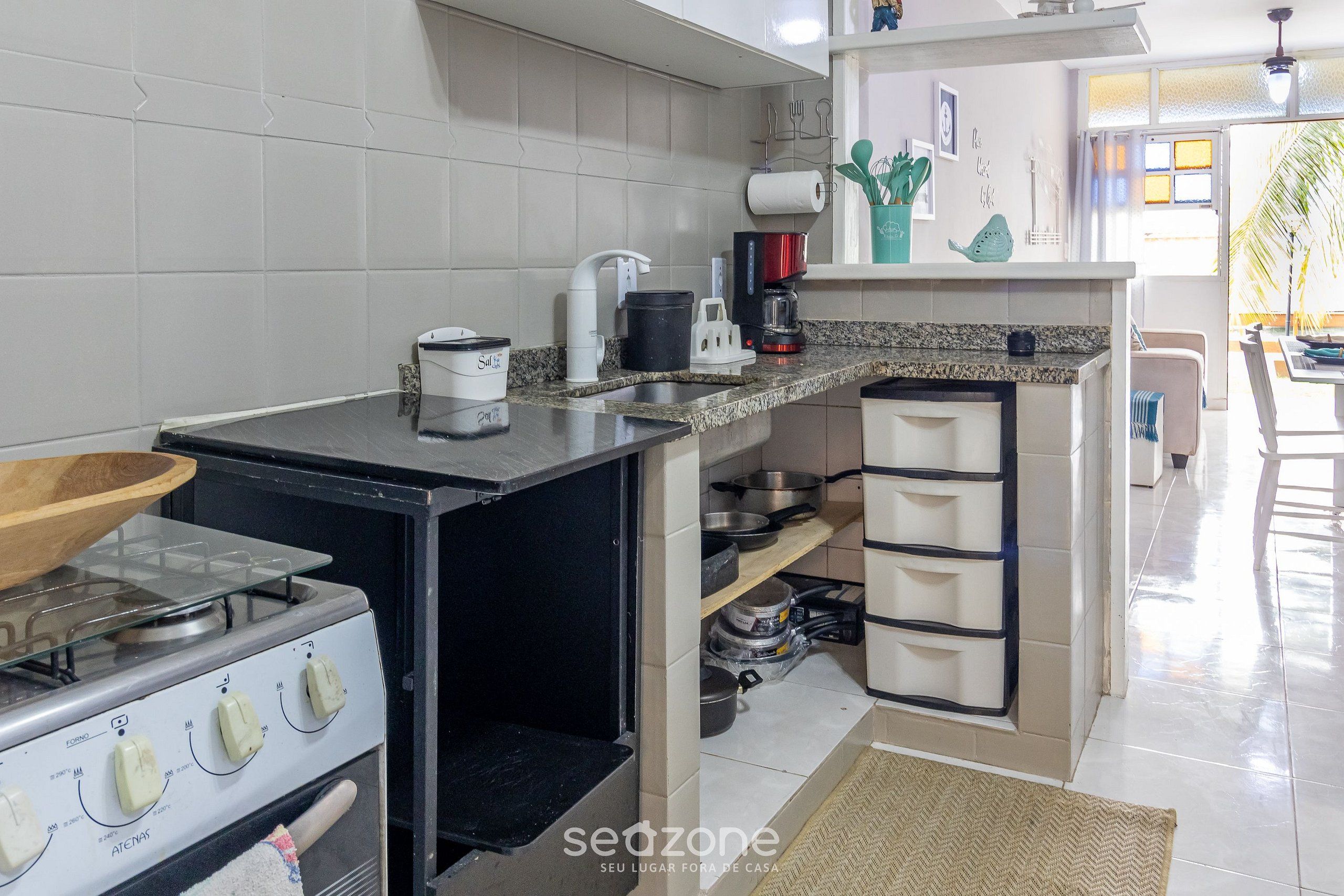 Uma cozinha compacta com fogão a gás, cafeteira e um pequeno balcão.