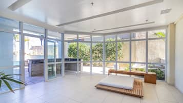 Una habitación amplia con ventanas grandes, un banco de madera y una cama.
