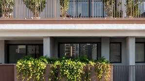 Un edificio de varios pisos con balcones, ventanas amplias y vegetación.