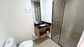 Un baño moderno con inodoro, lavamanos y cabina de ducha de vidrio.