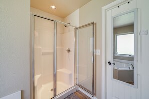 Un baño con ducha envuelta en vidrio, un lavamanos con espejo y una puerta con la leyenda 'privado'.