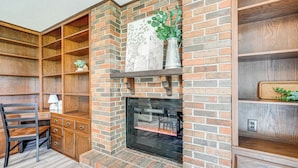 A brick fireplace with a mantel shelf, wooden shelving, and a desk with a chair. - 12 Mi to Mississinewa Lake: Peaceful Retreat (Amboy)