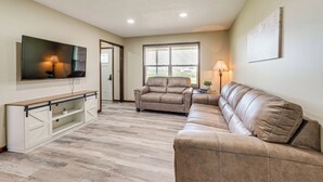 A living room with a sofa, a TV on a stand, a window with blinds, and a lamp. - 12 Mi to Mississinewa Lake: Peaceful Retreat (Amboy)