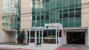 Egy modern épület, üveg homlokzattal, melyen az „EDIFICIO VENETO 520” felirat látható, és egy kis előtér, melyben egy virágtartó található.