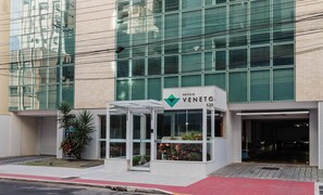 Ein modernes Gebäude mit Glasfassade, einer Beschilderung mit dem Schriftzug "EDIFICIO VENETO 520" und einem kleinen Eingangsbereich mit einem Blumentopf.