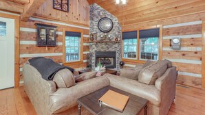 A cozy log cabin interior with a stone fireplace, leather sofas, and wooden walls. - Escape to the Mountains: Hot Tub Haven in Ellijay! (Ellijay)