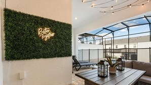 Une terrasse sur le toit agrémentée d’un mur végétal, d’une enseigne au néon, d’un espace clos par des parois de verre et de mobilier d’extérieur.