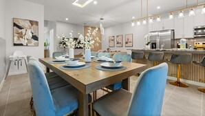 Un espace repas moderne avec une table en bois, des chaises bleues et un vase central orné de fleurs.