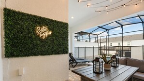 Terraço no telhado com parede verde, letreiro neon, área envidraçada e mobiliário para área externa.