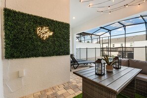 Terraço no telhado com parede verde, letreiro neon, área envidraçada e mobiliário para área externa.