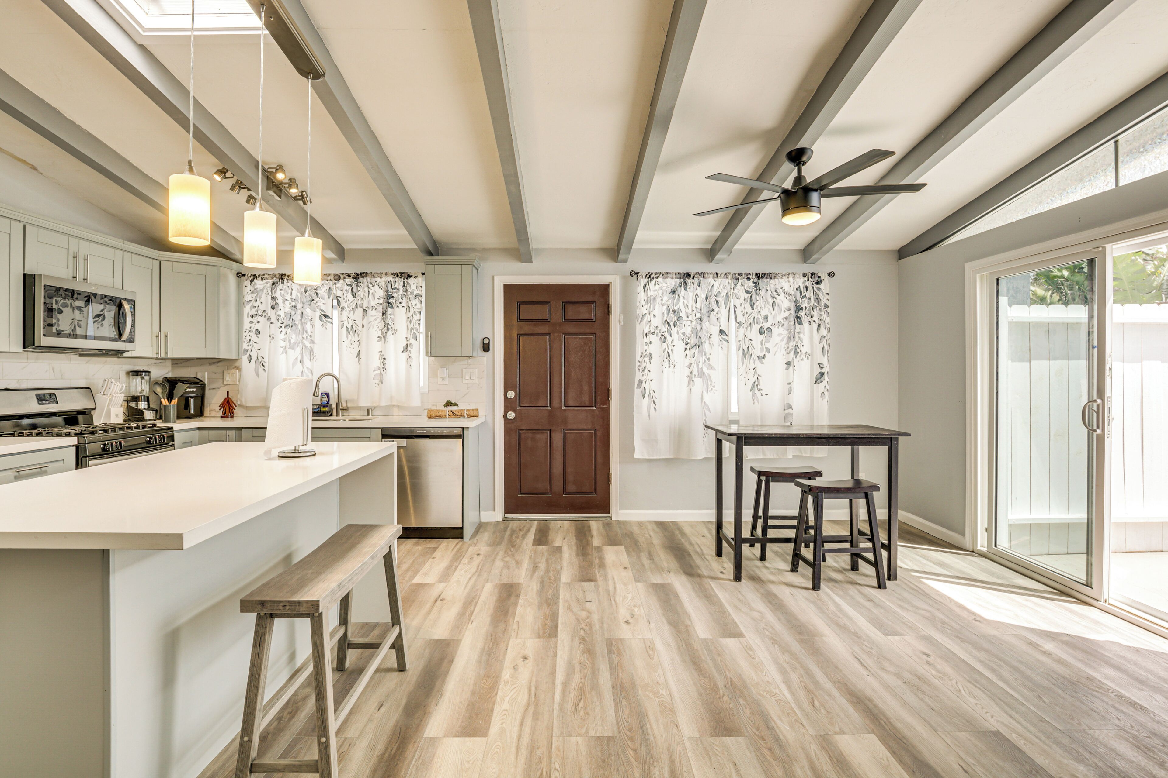 Una cocina moderna con una isla central, luces colgantes y un ventilador de techo.