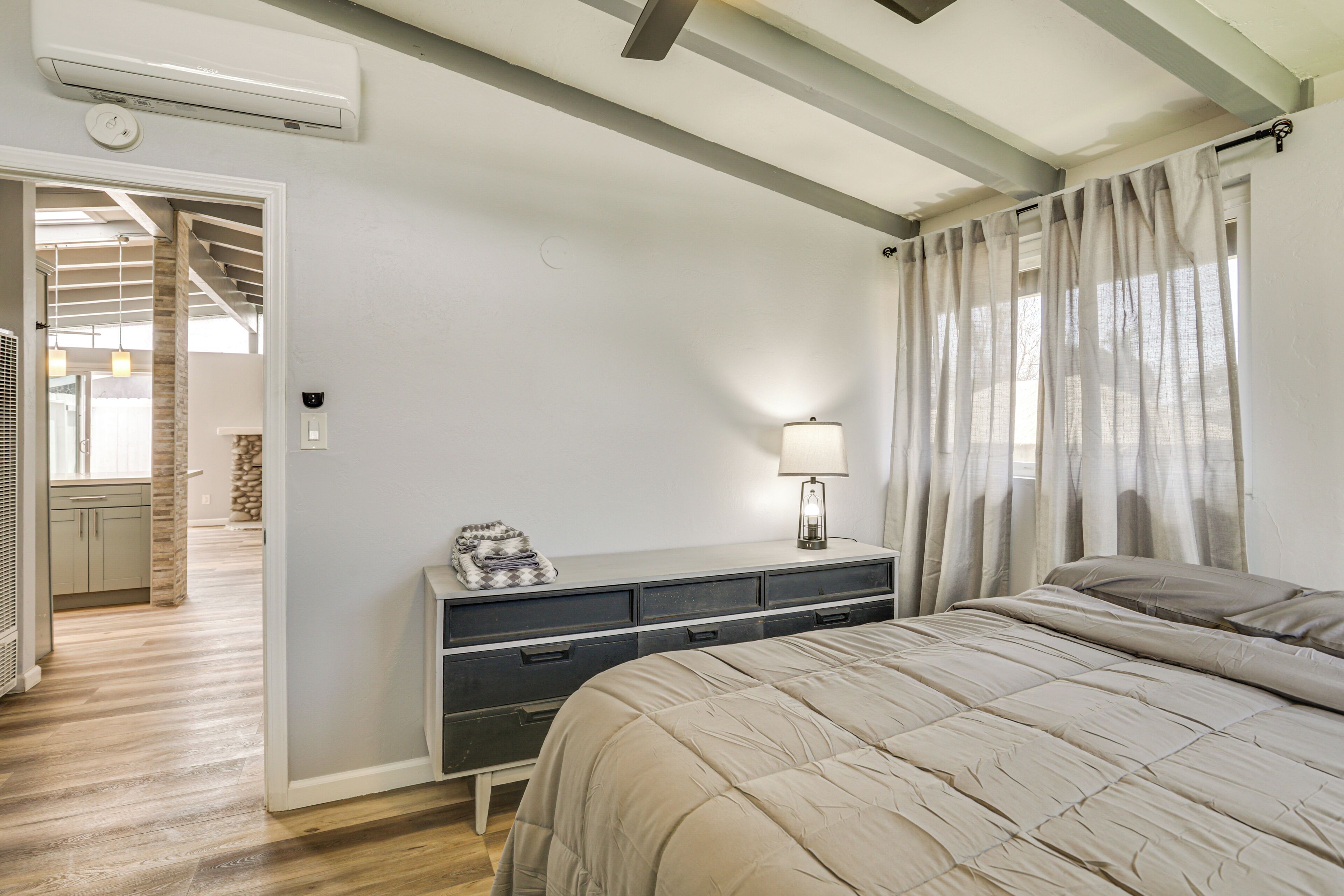 A bedroom with a bed, a bedside table with a lamp, and a dresser.
