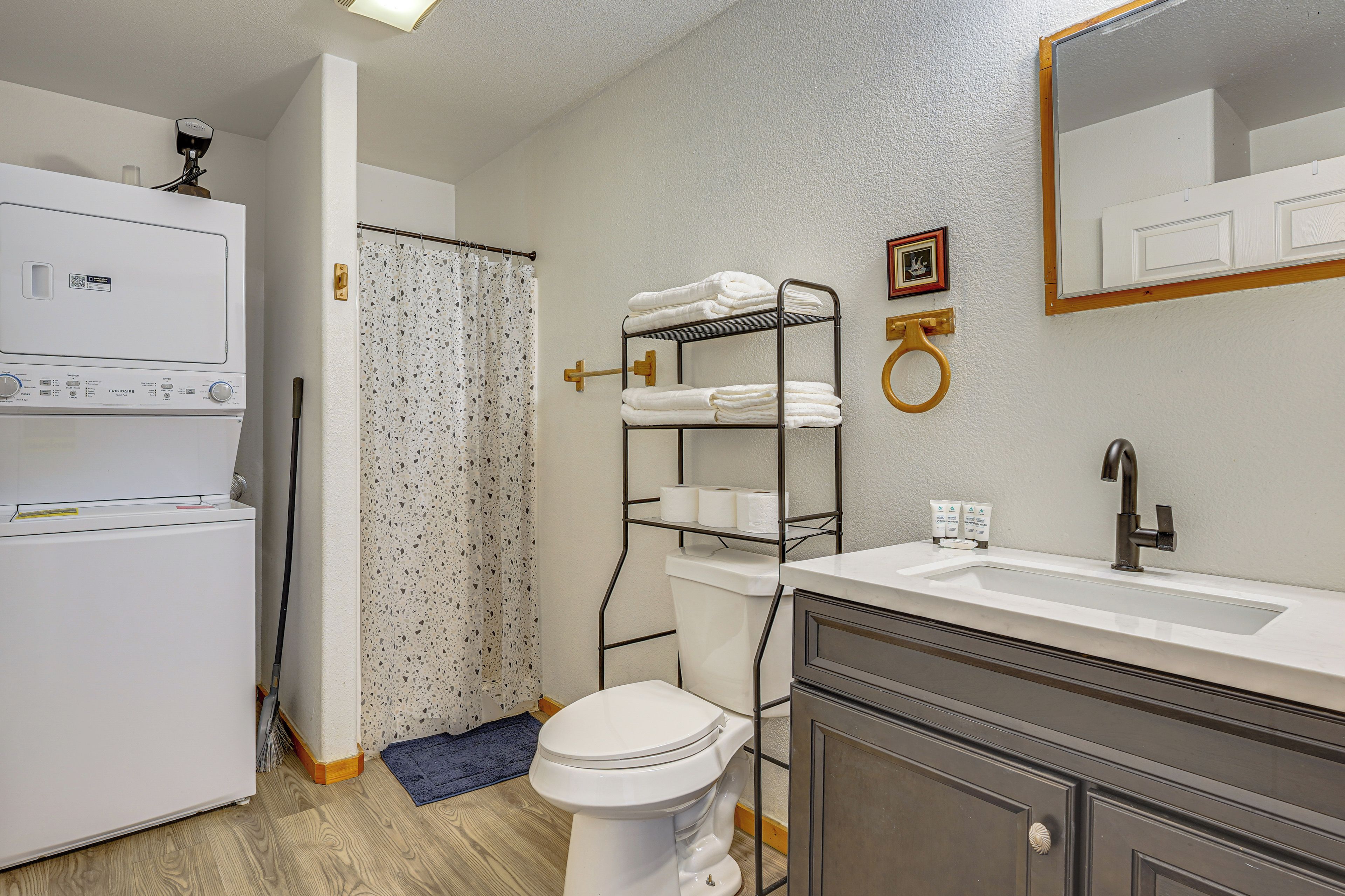 Een badkamer met een wit toilet, een wastafel met spiegel, een handdoekrek en een douchegordijn.