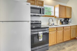 A kitchen with a stainless steel refrigerator, a microwave, a stove, and wooden cabinets.