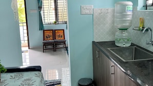 A compact kitchen with wooden cabinets, a sink, and a water dispenser.