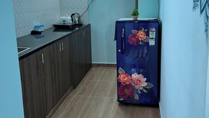 A narrow kitchen with dark wooden cabinets, a countertop, and a refrigerator with floral decals.