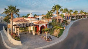 Een hotel in mediterrane stijl, met een centrale binnenplaats, palmbomen en uitzicht op zee.