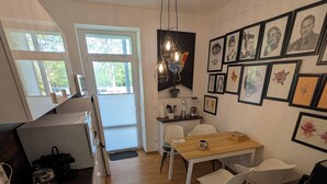 Une cuisine moderne avec un coin repas, un plancher en bois et un mur décoré d’œuvres d’art encadrées.