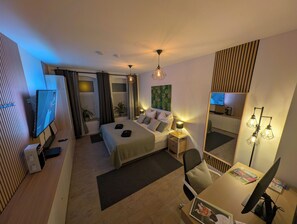 A modern hotel room with a bed, desk, chair, TV, and a mirror. - Studio with workplace and balcony in a quiet location close to the city. (Chemnitz)