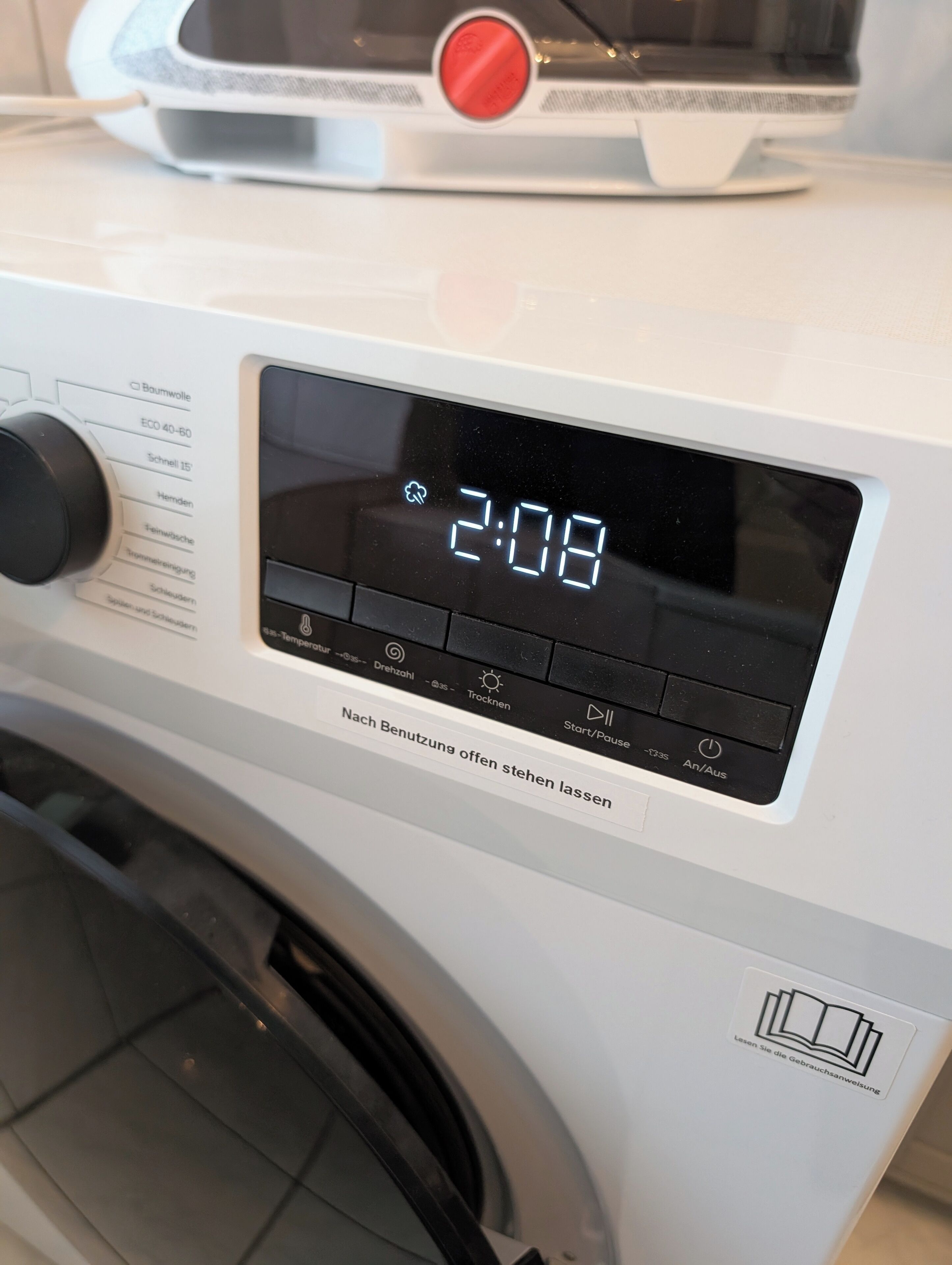 Un lave-linge à chargement frontal doté d’un écran numérique affichant 2 h 08.