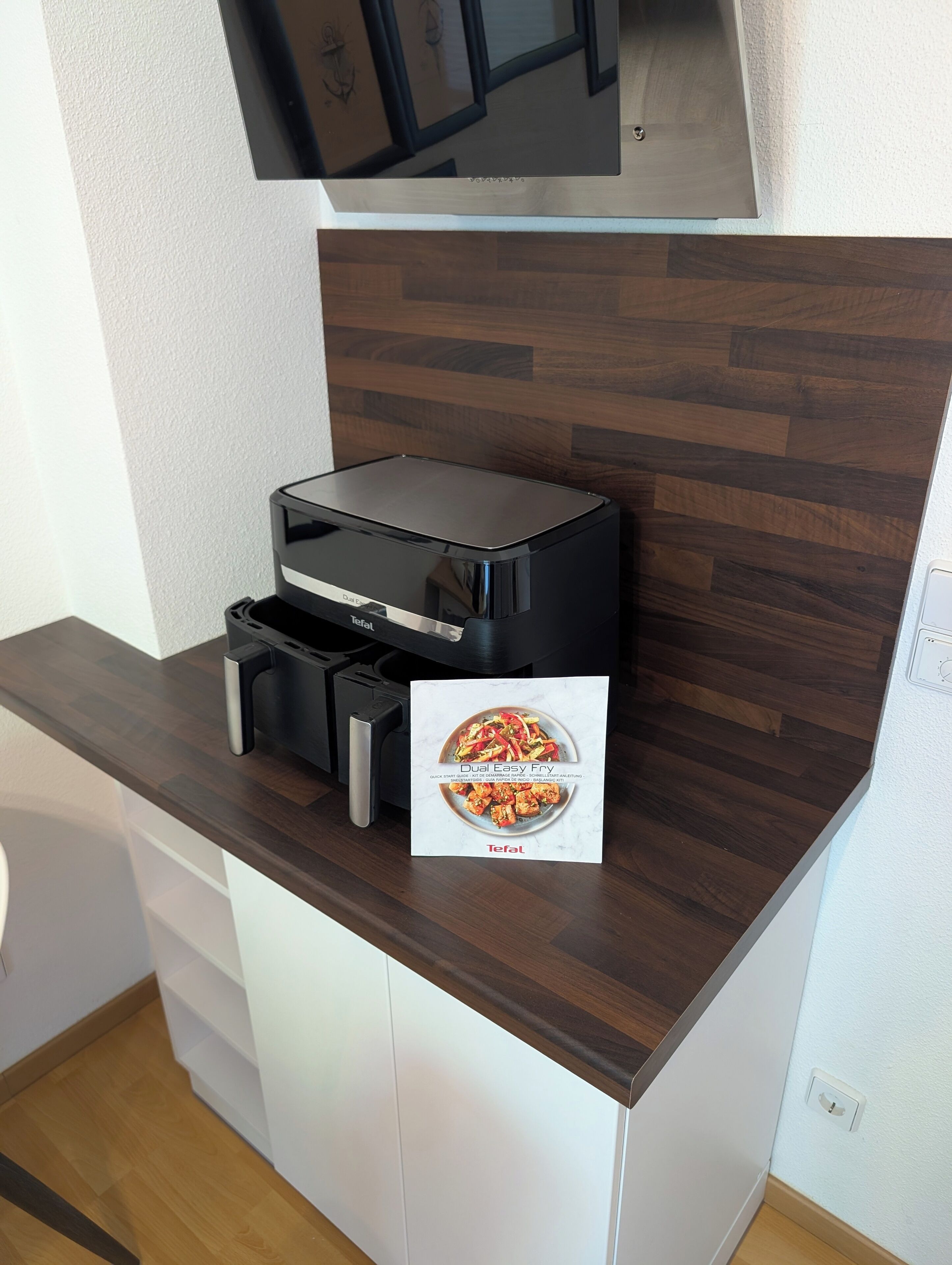 A kitchen with a dual fryer, a white cabinet, and a wooden countertop.