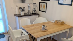 Un coin repas avec une table en bois, des chaises blanches et une tasse à café.
