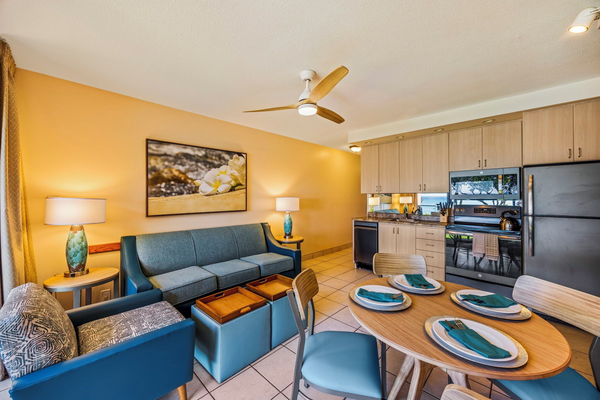 A modern living room with a sofa, a dining table set for four, and a kitchen area with cabinets and appliances.