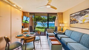 A hotel room with a dining area, a sofa, a TV, and a view of the ocean. - Kuleana Club - 404 (Lahaina)