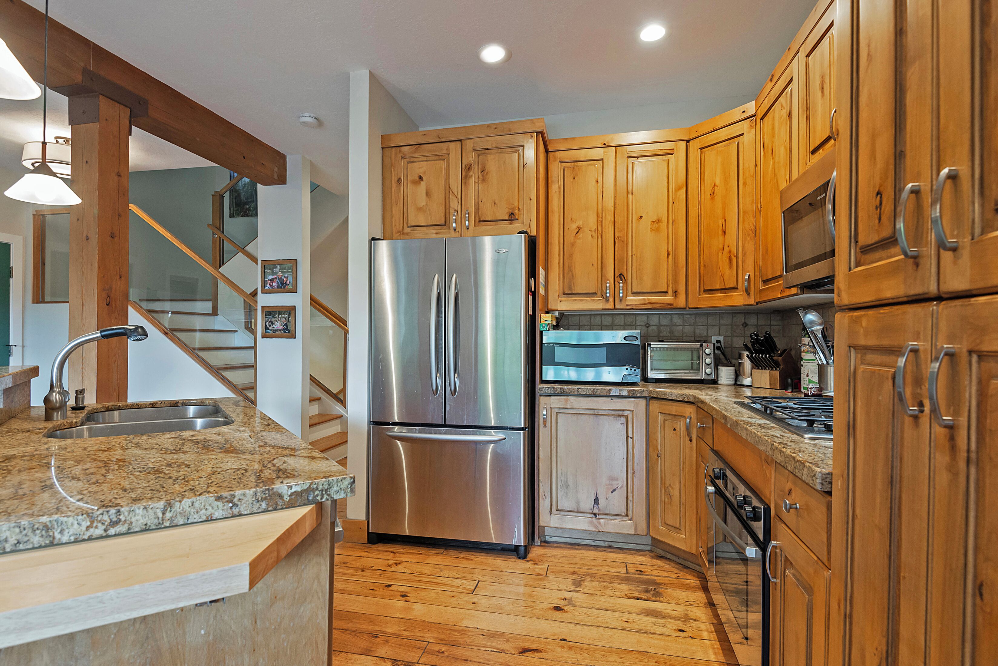 A modern kitchen with wooden cabinets, stainless steel appliances, granite countertops, and a built-in oven.