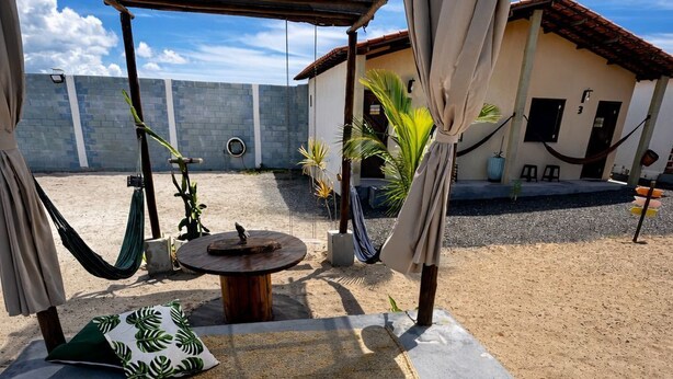 A covered outdoor seating area with a hammock, a round table, and a woven mat. - Canto das Praieiras (Entre Rios)