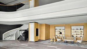 A modern lobby with a curved staircase, a reception area, seating, and a wall with shelves. - Fairfield By Marriott Shunde (Foshan)