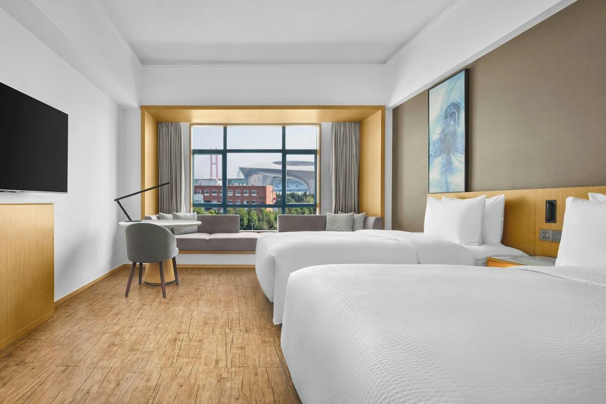 Een hotelkamer met een groot bed, een bureau, een stoel en een televisie.