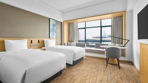 A hotel room with two beds, a desk, a chair, a large window with a view, and a TV. - Fairfield By Marriott Shunde (Foshan)