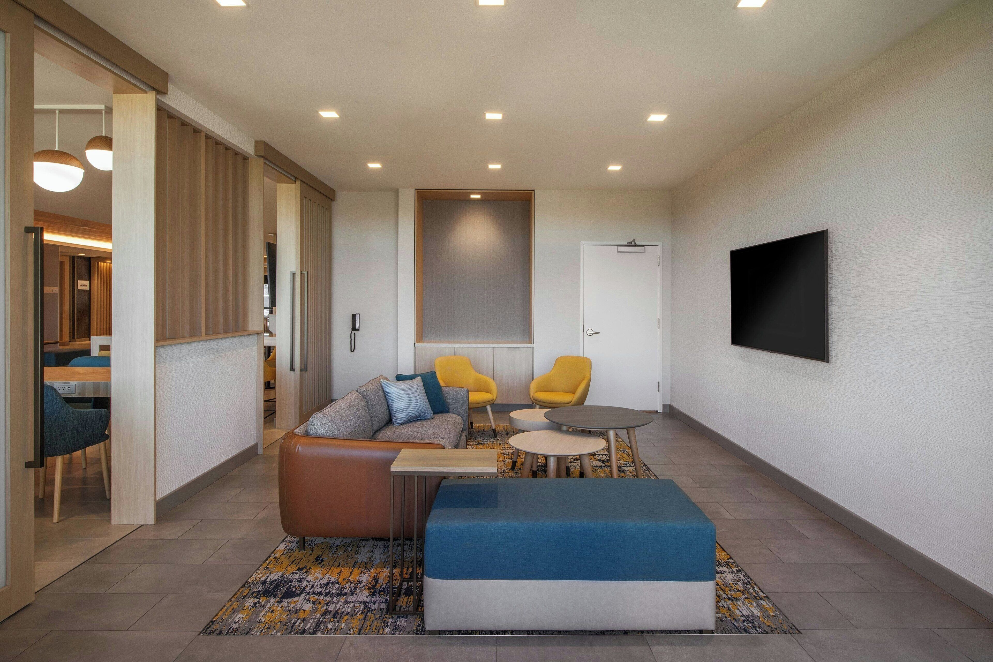 A modern living room with a sofa, two armchairs, a coffee table, and a TV mounted on the wall.