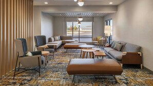 A modern hotel lobby with a seating area, sofas, armchairs, and a patterned carpet. - Towneplace Suites By Marriott Great Falls (Great Falls)