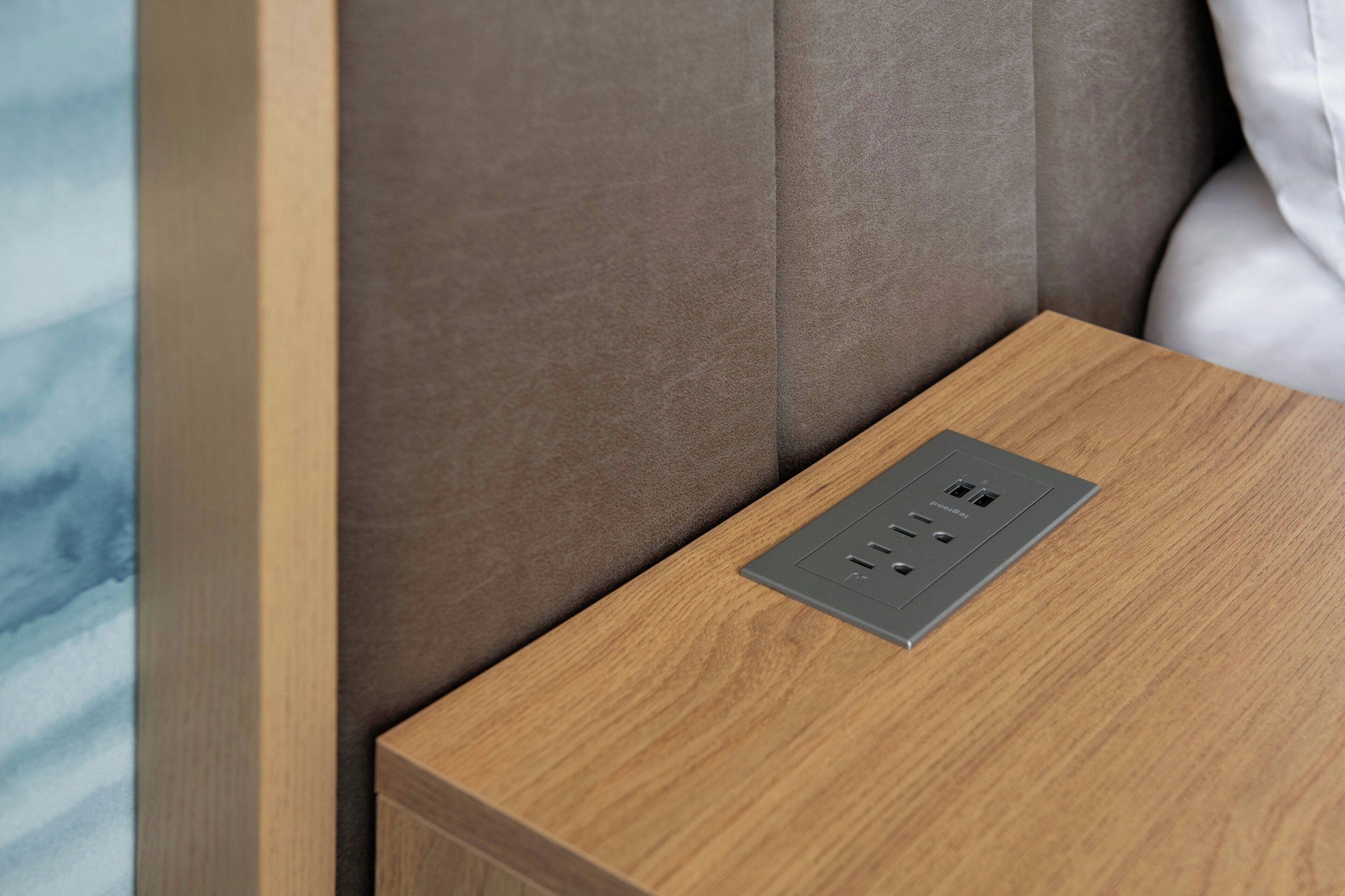 A wooden bedside table with a built-in power outlet.